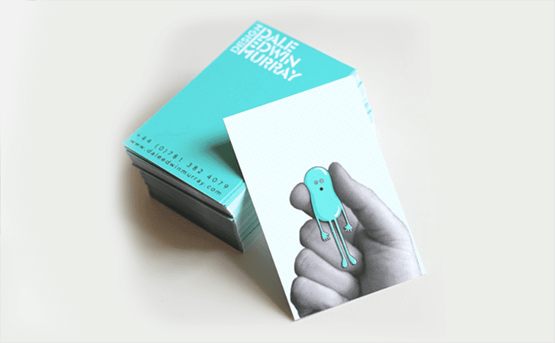 a hand holding a blue bird brochure on top of a white table.